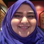 Amina papa wearing purple hijab, looks at the camera and smiles